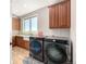 Bright laundry room with dark front-loading washer and dryer, generous cabinet space and utility sink at 15501 Fairway Dr, Commerce City, CO 80022