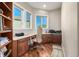 A home office with wood floors, built-in shelves, wood cabinets, and three windows at 15501 Fairway Dr, Commerce City, CO 80022
