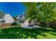A serene backyard featuring a well-manicured lawn, established trees, and a stone patio with an outdoor dining set at 21238 Snowshoe Ln, Parker, CO 80138