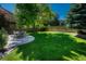 A spacious backyard features a lush lawn, mature trees, a wooden fence and a stone patio with a dining table at 21238 Snowshoe Ln, Parker, CO 80138