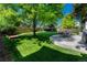 Large backyard features lush green grass, mature trees providing shade, a stone patio with outdoor dining set, and a wooden fence at 21238 Snowshoe Ln, Parker, CO 80138