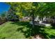 This home features a sprawling backyard with lush lawn, mature trees, a wooden fence, and a patio area for entertaining at 21238 Snowshoe Ln, Parker, CO 80138