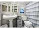 Charming bathroom with pedestal sink, marble-style walls and blue and white shower curtain at 3623 S Sheridan Blvd # 12, Denver, CO 80235