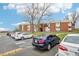 View of an apartment building with a parking lot, and trees nearby on a bright day at 3623 S Sheridan Blvd # 12, Denver, CO 80235