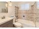 Compact bathroom featuring a tub with a tiled shower surround, a modern vanity, and decorative lighting at 7251 Larsh Dr, Denver, CO 80221