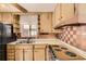 Functional kitchen featuring wood cabinetry, an older cooktop, and tiled backsplash, creating a nostalgic cooking space at 7251 Larsh Dr, Denver, CO 80221