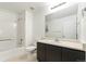 Bright bathroom featuring a shower-tub combo, black vanity, a sleek mirror and neutral tile flooring at 9847 Helena Ct, Commerce City, CO 80022