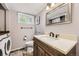 Cozy bathroom with modern vanity, tile floors, and convenient washer/dryer unit at 10621 Julian St, Westminster, CO 80031