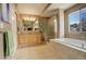 Bright bathroom features a soaking tub, tiled shower, double vanity, and large window at 5830 Jasper Pointe Cir, Castle Pines, CO 80108