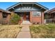 Charming brick home featuring a covered porch, red front door, and well-maintained lawn at 618 Adams St, Denver, CO 80206