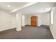 Spacious finished basement with neutral carpet and a rustic wood cabinet against a white wall at 7527 E Severn Pl, Denver, CO 80230