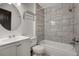 Bright bathroom featuring a white vanity, round mirror, and tiled shower-tub combo at 677 Vrain St # 5, Denver, CO 80204