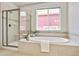 Bathroom showcasing a tub, glass shower and a window letting in natural light at 16283 Olive Way, Brighton, CO 80602