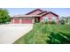 Well-maintained home featuring a lush front lawn, a long driveway, and a two-car garage at 16283 Olive Way, Brighton, CO 80602