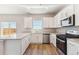 Well-lit kitchen with white cabinets, stainless steel appliances, quartz countertops and wood laminate floors at 48220 Shetland Dr, Bennett, CO 80102