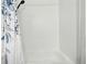 Bathtub with bright, white tile walls and a shower with floral-patterned shower curtain at 15034 E Floyd Ave, Aurora, CO 80014