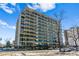 Low angle shot of a high-rise condo building showing many private balconies, blue sky and leafless tree in the foreground at 888 N Logan St # 5A, Denver, CO 80203