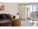Relaxing living room featuring a comfortable brown sofa, wicker ottoman, and access to a private balcony at 888 N Logan St # 5A, Denver, CO 80203