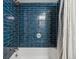 Close-up of blue tiled shower with white tub and chrome fixtures at 888 N Logan St # 5A, Denver, CO 80203