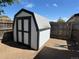 Backyard storage shed featuring barn doors and a modern grey and white paint scheme at 8362 Jasmine St, Commerce City, CO 80022