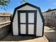 White storage shed with black trim and barn doors located in the backyard of the property at 8362 Jasmine St, Commerce City, CO 80022
