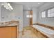 Bright bathroom features tiled floors, wood cabinets, a tub and a window with natural light at 1012 S Addison Way, Aurora, CO 80018