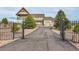 Gated driveway leading to a stately home, featuring a porch, three-car garage, and professionally landscaped grounds at 1012 S Addison Way, Aurora, CO 80018