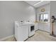 Bright laundry room featuring front loading washer and dryer, folding counter, and window with backyard view at 1012 S Addison Way, Aurora, CO 80018