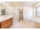 Bright bathroom with a soaking tub, glass shower, and a vanity with wood cabinets at 6271 S Billings Way, Centennial, CO 80111