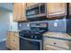 Close up of kitchen area with black gas range and oven, granite countertop, and stainless steel microwave at 3200 W Chenango Ave, Englewood, CO 80110