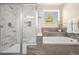 Bathroom featuring tiled soaking tub, shower, and window with view of greenery at 3309 Thornwood Ct, Castle Rock, CO 80108