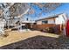 Fenced backyard with mature trees, covered patio, and brick accents on the back of the home at 6851 S Franklin St, Centennial, CO 80122