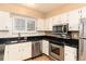 Modern kitchen featuring stainless steel appliances, sleek black countertops, and bright white cabinetry at 6851 S Franklin St, Centennial, CO 80122