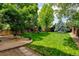 Spacious backyard featuring a lush green lawn, mature trees, and a charming playset for outdoor fun at 7245 Prairie Cir, Longmont, CO 80504