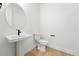 Modern powder bathroom with a pedestal sink, oval mirror, and white fixtures at 1733 Fox Trotter Pt, Castle Rock, CO 80104