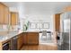 Open kitchen with wooden cabinets, stainless steel appliances, and an adjacent dining area at 3930 S Spruce St, Denver, CO 80237