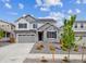 Beautiful two-story home featuring stone accents, gray siding, a two-car garage, and manicured landscaping at 25323 E Warren Pl, Aurora, CO 80018