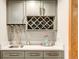 Chic wet bar area with gray cabinetry, gold hardware, a built-in wine rack, and a stylish countertop at 5745 W Mansfield Ave # 265, Denver, CO 80235