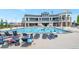 Community swimming pool with lounge chairs, an umbrella, and a large two story building in the background at 6988 S Riverwood Way, Aurora, CO 80016