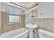 Classic bathroom featuring a tub with shower, pedestal sink, and tiled walls and floor at 2100 N Franklin St # 15, Denver, CO 80205