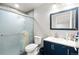 Bathroom featuring a glass shower, blue vanity and a sink with a large framed mirror at 16673 E Kent Dr, Aurora, CO 80013