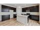 Modern kitchen featuring stainless steel appliances, an island, dark cabinets, and wood flooring at 5918 Red Barn Ave, Mead, CO 80504