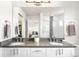 Modern bathroom featuring dual sinks with gray countertops, white cabinets, and a large mirror showcasing the shower and bedroom at 883 Widgeon Cir, Longmont, CO 80503