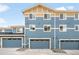 Townhome exterior displaying a blue facade with three garage doors and neatly maintained landscaping at 883 Widgeon Cir, Longmont, CO 80503