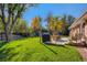 This backyard features a spacious lawn, patio seating, a shed, and mature trees at 6642 S Pearl St, Centennial, CO 80121