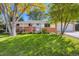 Inviting single-story home with a well-kept lawn, brick accents, covered porch, and an American flag on display at 6642 S Pearl St, Centennial, CO 80121