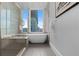 Luxurious bathroom features a soaking tub, glass shower, and modern fixtures with city views at 155 Steele St # 917, Denver, CO 80206