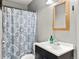 Compact bathroom with vanity and patterned shower curtain, offering a functional space at 8991 Hickory Pl, Thornton, CO 80229