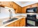 Kitchen featuring wood cabinets, stainless steel sink, and a black oven and microwave combo at 4923 Pinon Dr, Elizabeth, CO 80107