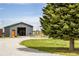 View of an outbuilding with green trim, an orange door, gravel driveway and mature trees at 6310 W County Road 4, Berthoud, CO 80513